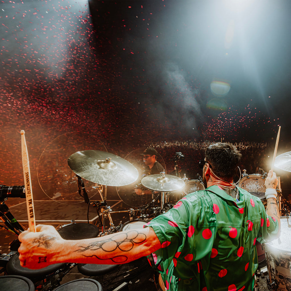Shannon Leto in a green jacket with red polka dots playing drums on stage with confetti.