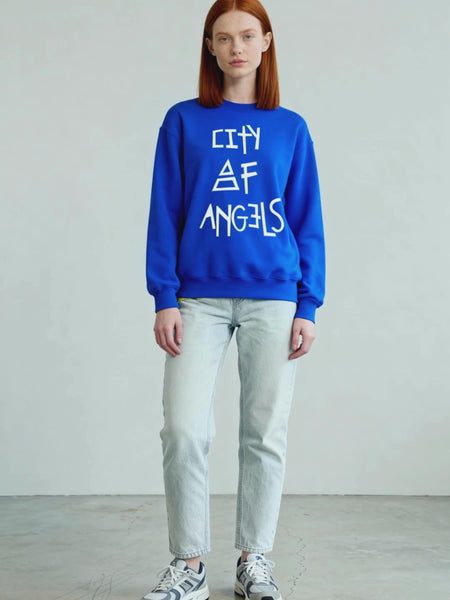 Video of female model wearing the royal blue City of Angels graphic print sweatshirt, standing against a neutral backdrop. 